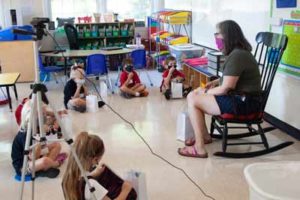 teacher in rocking chair with students on floor
