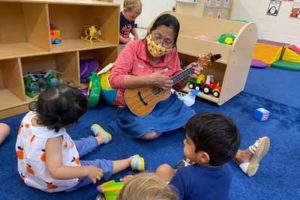 c38a7361e22c4187b2619cb94e2ed0c9 Teacher playing guitar with toddlers